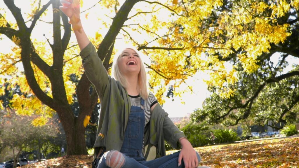 Emma sitting cross-legged under a tree, reaching toward the sunlight. A suicide attempt left Emma paralyzed but propelled her on a mission to help others.