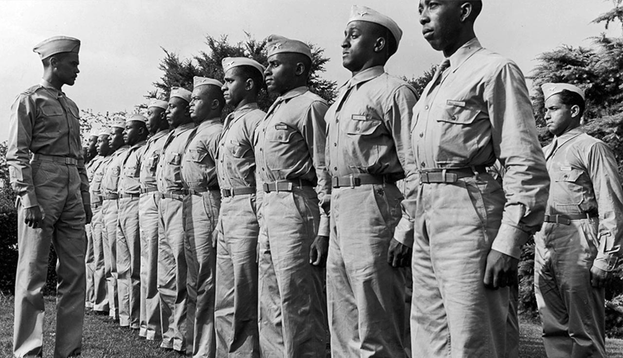 Black soldiers of WWII standing at attention while their captain address them.