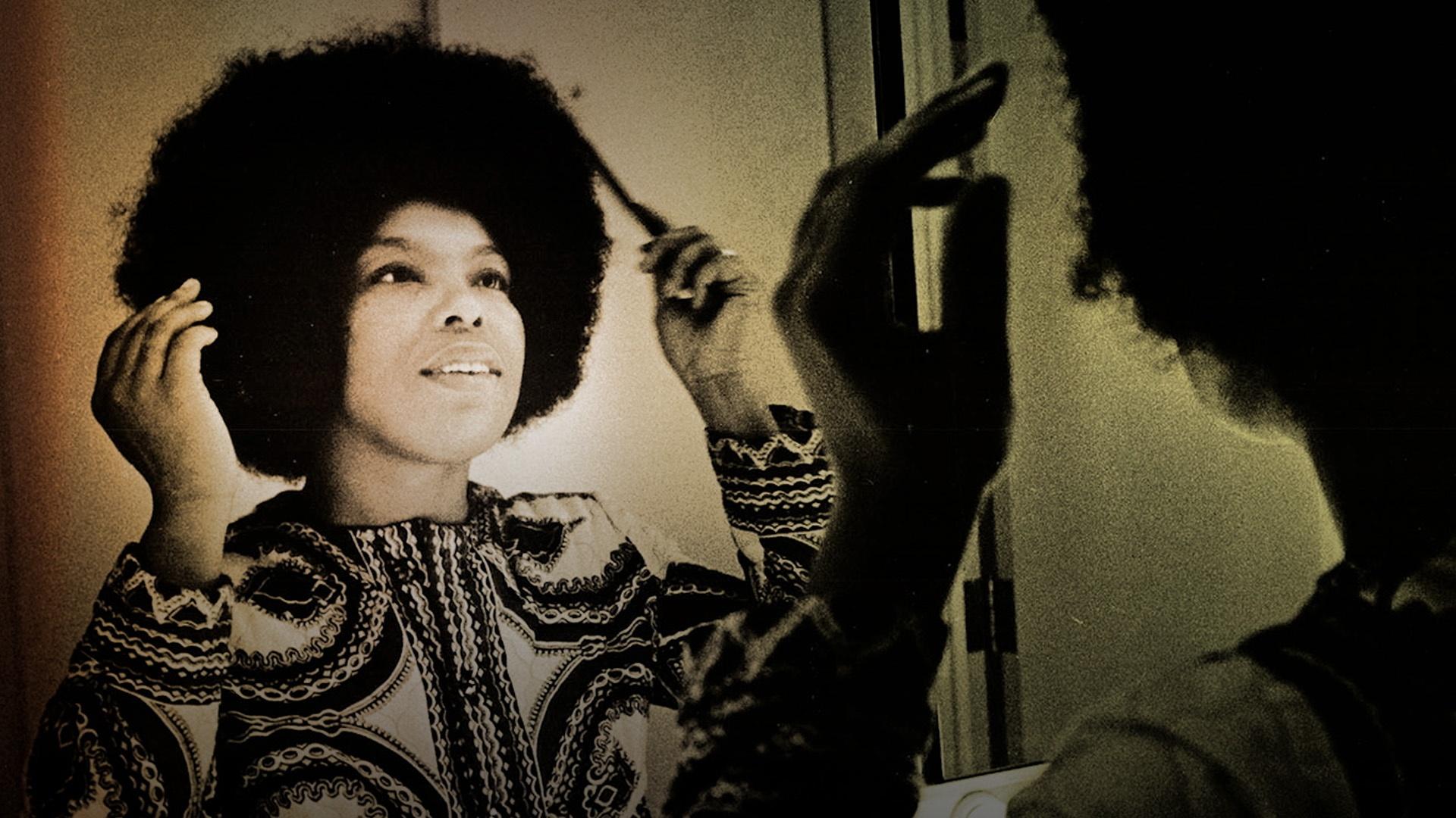 A Black woman looking into a mirror to comb her Black hair