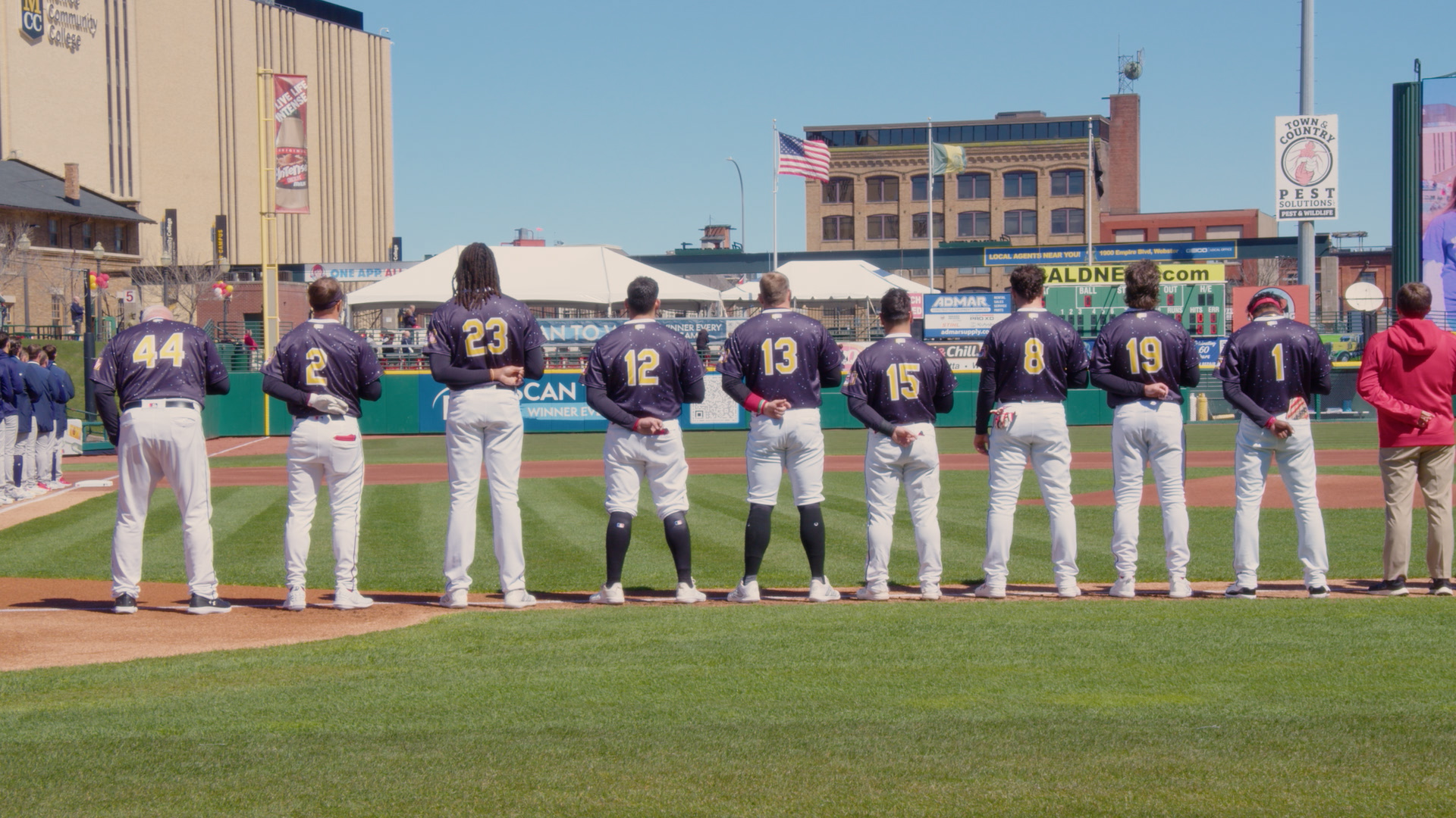 A photo of the back of a baseball team standing for the National Anthem