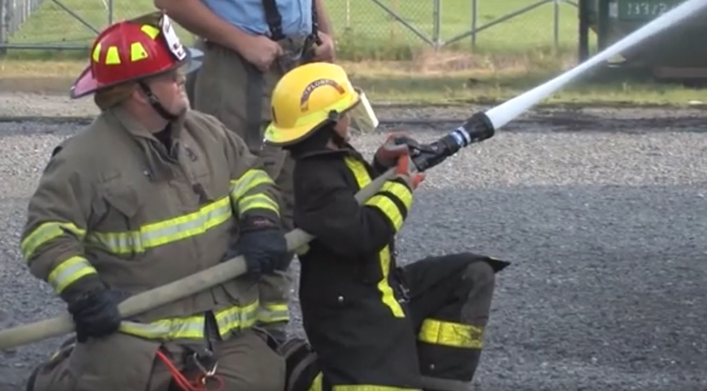 Two Firefighters using a fire hose in a training program