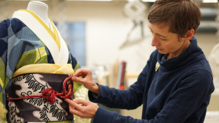 A textile display expert ties an obijime around the Wafrica Kimono by Serge Mouangue