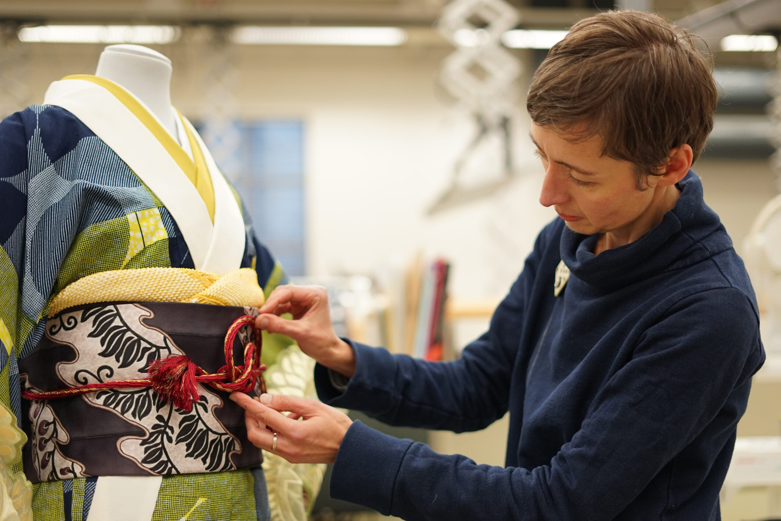 A textile display expert ties an obijime around the Wafrica Kimono by Serge Mouangue