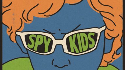 Film poster of a boy with blue skin and orange hair wearing glasses with green type that reads SPY KIDS