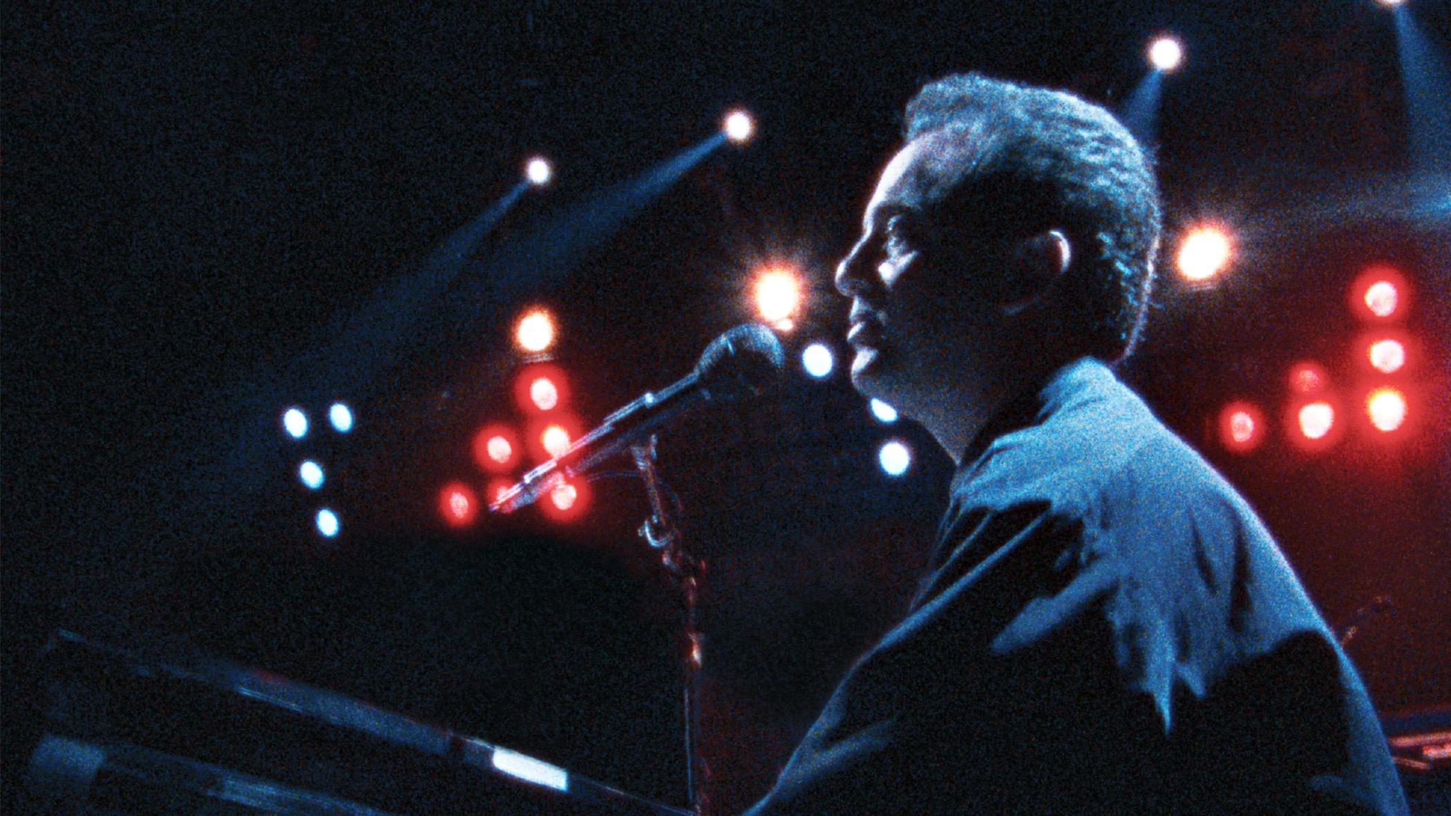 Billy Joel at a piano singing on stage at Yankee Stadium