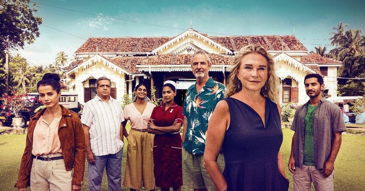 Eight cast of The Good Karma Hospital stand outside in front of a white cottage hospital.