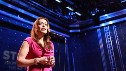 Growing Up Latina: A Latina on stage speaks into a microphone