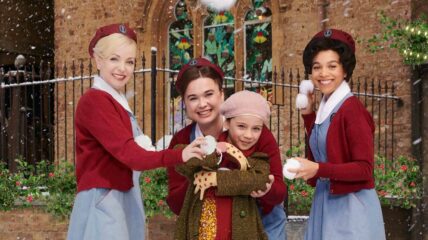 Three nurse stand holding snowballs. The nurse in the middle is hugging a child.