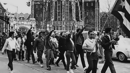 Black and Puerto Rican students march through campus with the Puerto Rican flag