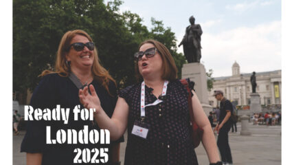 Two women one with blonde hair, one with brown hair both wearing sunglasses and Black bouses stand outside