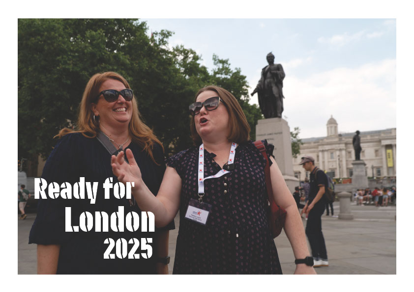 Two women one with blonde hair, one with brown hair both wearing sunglasses and Black bouses stand outside