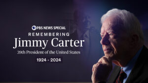 President Jimmy Carter wearing a blue suit with a blue shirt and red and blue tie.