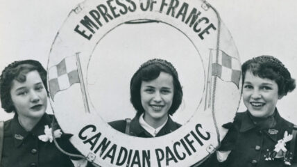 Three young women on a ship holding a buoy that reads: Empress of France Canadian Pacific